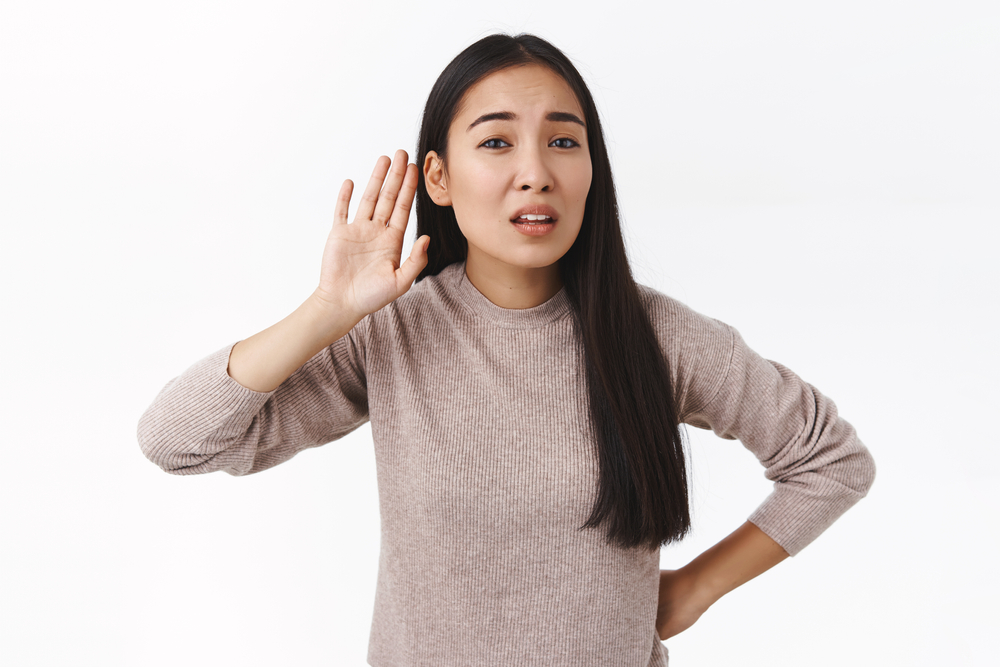 women holding hand up to ear