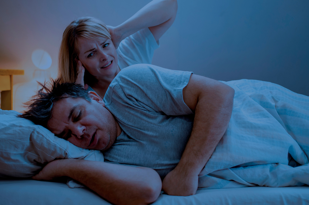 couple in bed; man snoring, wife covering ears