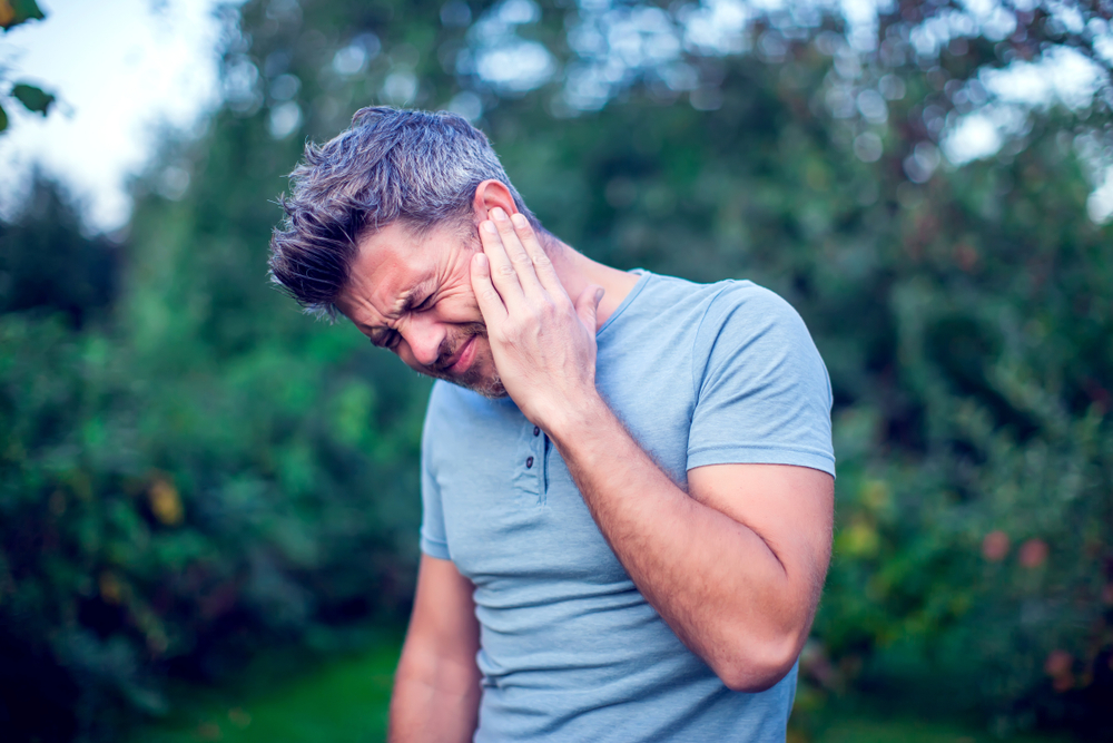 man holding his ear in pain